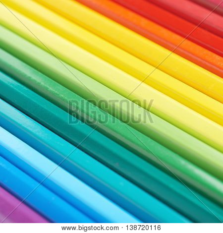 Multiple colorful color pencils composition arranged in a line to form a rainbow gradient, close-up crop fragment