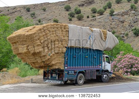 ATLAS, MOROCCO - JULY 10: Overloaded truck staying on road, July 10, 2013 in Atlas Mountains, Morocco. Road in Atlas Mountains very popular tourist route in central Morocco.