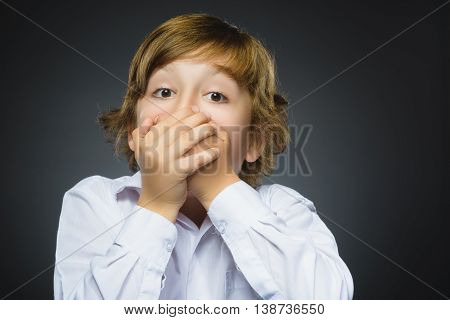 Closeup Portrait of handsome boy with astonished expression while standing against grey background.