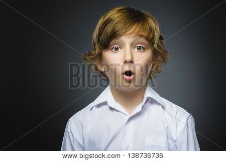 Closeup Portrait of handsome boy with astonished expression while standing against grey background.