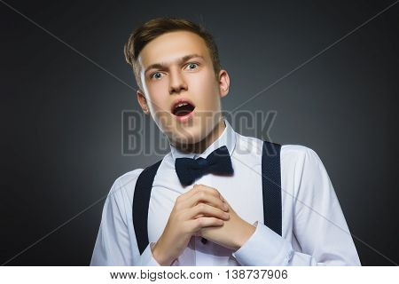 Closeup Portrait of handsome boy with astonished expression while standing against grey background.
