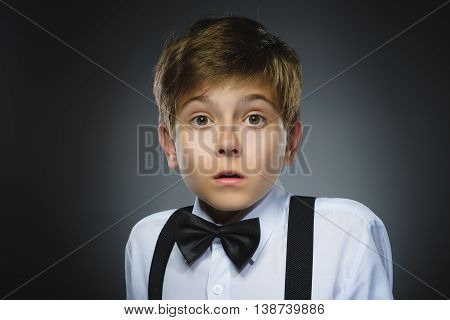 Closeup Portrait of handsome boy with astonished expression while standing against grey background.