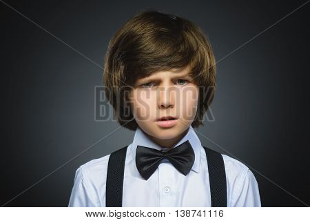 Closeup Portrait of handsome boy with astonished expression while standing against grey background.