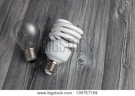 Energy-saving lamp and incandescent bulb on wooden background. Sales of light bulbs. Advertising on lighting technology.
