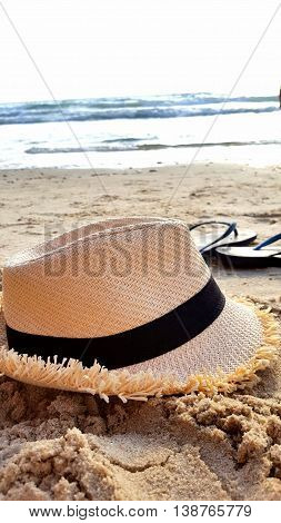 hat and flip- flops on the beach