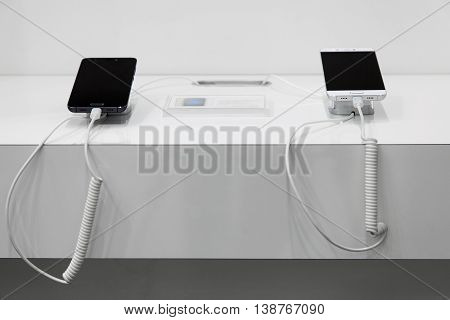 Two smartphones on a white showcase with antitheft system