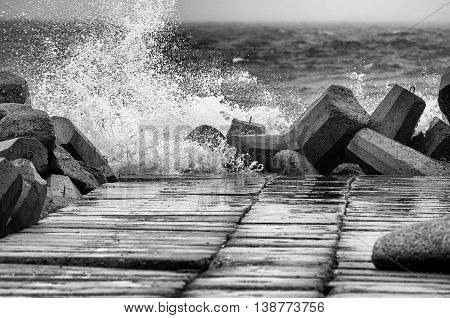 Concrete breakwater in black and white with rough sea