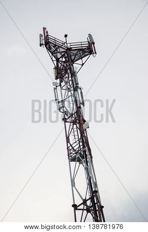 Base transceiver station (BTS) with antenna isolated on blue sky background. Telecommunications radio tower cells