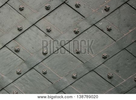 Detail of wrought iron door with a metal plate twisted and sculpted nails