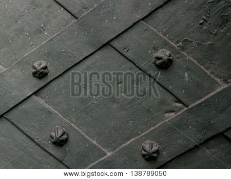 Detail of wrought iron door with a metal plate twisted and sculpted nails. close-up