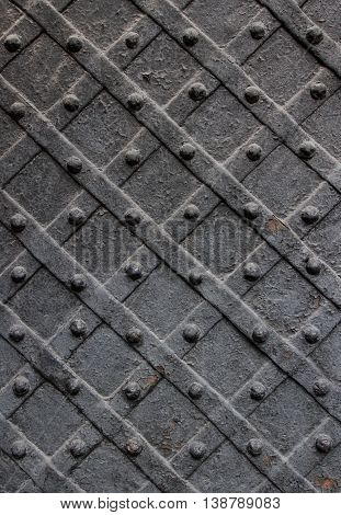 Detail of wrought iron door with a metal plate twisted and sculpted nails