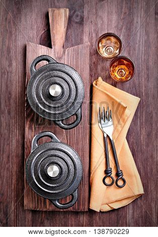 The small cast iron pan with forks and glasses on a cutting board