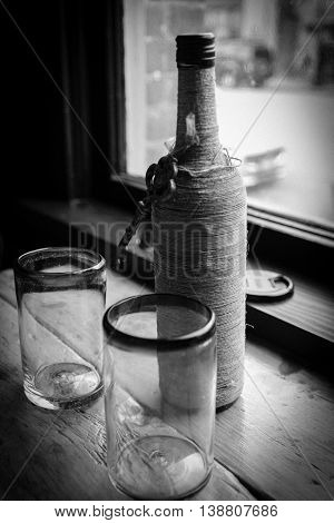 A water bottle and two glasses by the window