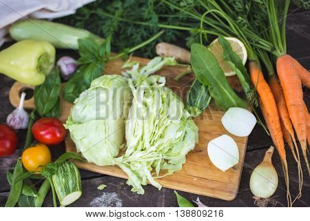 Closeup of fresh locally grown organic chopped vegetables on a cutting board on a wooden background. Vegan recipe.