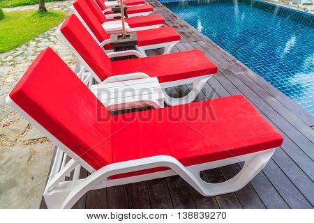 Beautiful beach chairs with umbrella around outdoor swimming pool neary sand and sea