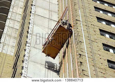 construction suspended yellow cradle with workers on a newly built high-rise building in Moscow