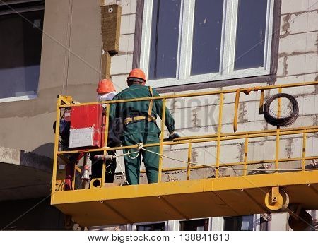 construction suspended yellow cradle with workers on a newly built high-rise building in Moscow
