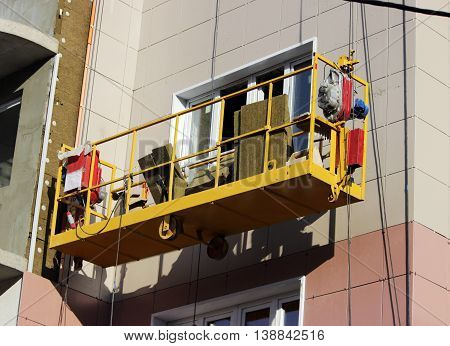 construction suspended yellow cradle without workers on a newly built high-rise building in Moscow