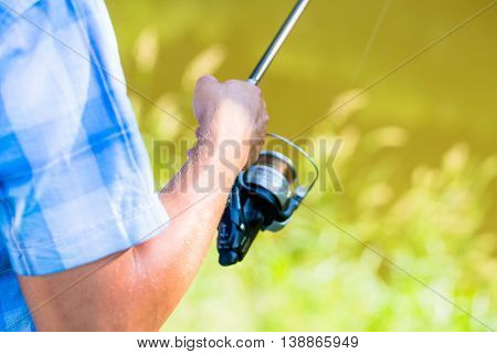 Close shot of sport fisherman reeling in the line on his fishing rod