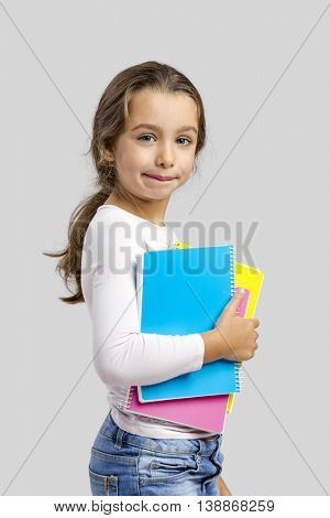 Smiling little student girl holding notebooks