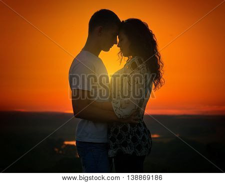 young couple at sunset on sky background, love concept, romantic people
