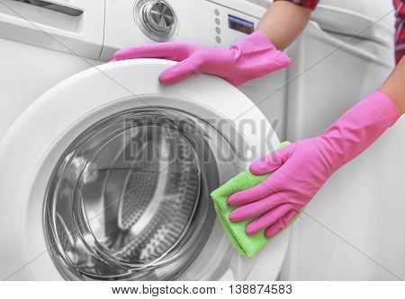 Female hands in gloves washing washing machine. Close-up.