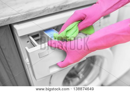 Female hands in gloves washing washing machine. Close-up.