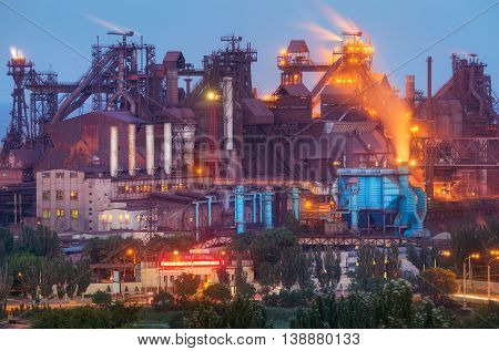 Metallurgical plant at night. Steel factory with smokestacks . Steelworks iron works. Heavy industry in Europe. Air pollution from smokestacks ecology problems. Industrial landscape at twilight