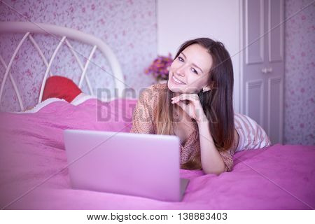 female using a laptop sitting on a bed