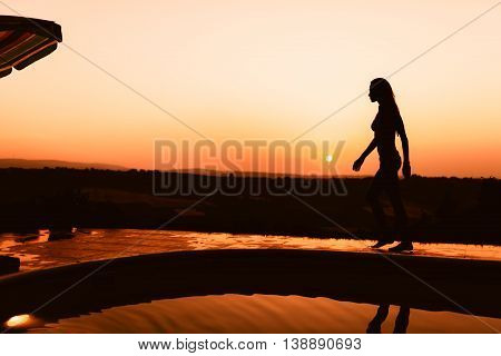 Beautiful woman enjoying summer sunet by her pool