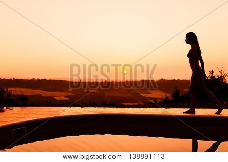 Beautiful woman enjoying summer sunet by her pool