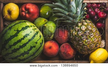 Summer friut variety on wooden background, top view. Watermelon, pineapple, lemon, figs, peach, sweet cherry and apple