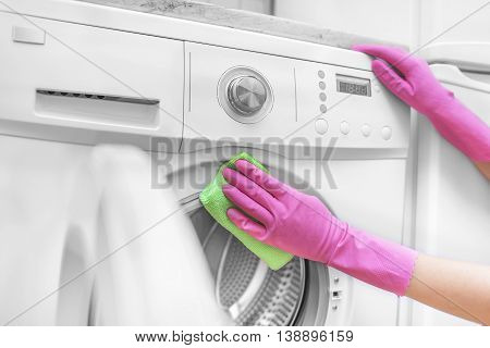 Female hands in gloves washing washing machine. Close-up.