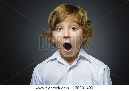 Closeup Portrait of handsome boy with astonished expression while standing against grey background.