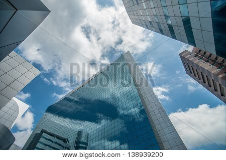 Modern glass skycrapers background with sky and clouds reflection