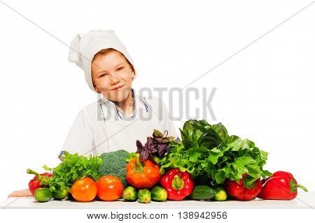 Happy kid boy in cook's uniform, preparing healthy vegetables meal, isolated on white background