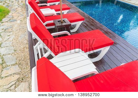 Beautiful beach chairs with umbrella around outdoor swimming pool neary sand and sea