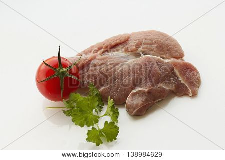 red raw meat piece with vegetables and greens on a white background