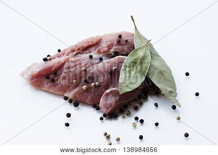 red raw meat piece with vegetables and greens on a white background