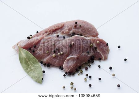 red raw meat piece with vegetables and greens on a white background