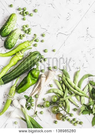 Fresh green vegetables - zucchini cucumbers green peas and beans parsnips peppers tomatoes onions on a white background. Vegetarian vegan table