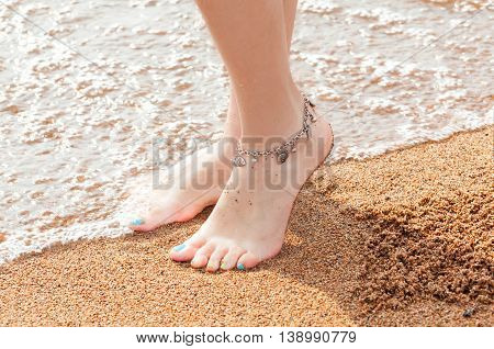 close-up of legs and a piece of jewelry for your feet. Young adult woman feet and toes, wearing anklet ankle bracelet resting in a summer vacation trip.