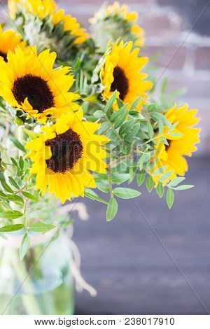 Bouquet Of Bright Sunflowers In A Glass Jar On A Wooden Table.