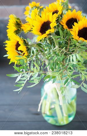 Bouquet Of Bright Sunflowers In A Glass Jar On A Wooden Table.