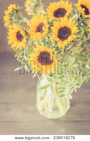 Bouquet Of Bright Sunflowers In A Glass Jar On A Wooden Table. Retro Toned.