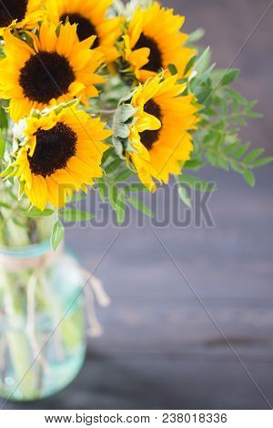 Bouquet Of Bright Sunflowers In A Glass Jar On A Wooden Table.