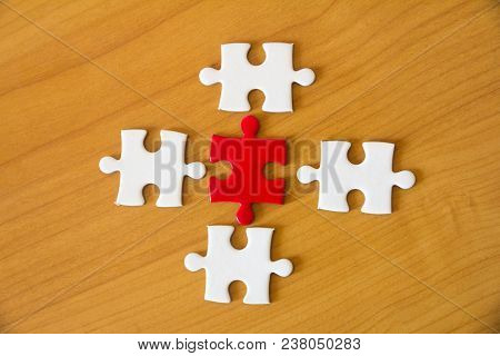 White And Red Jigsaw On The Wood Table, Teamwork Concept.