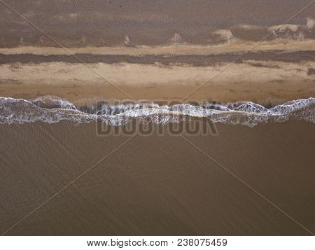 Aerial photo waves crashing on shingle beach