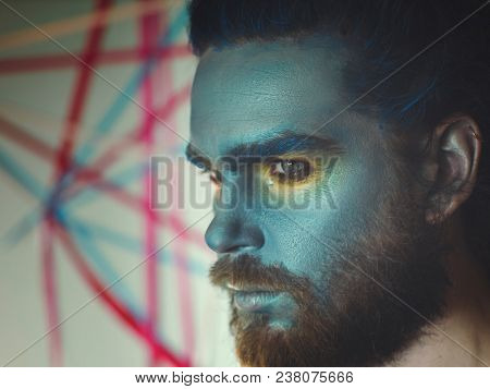 Portrait of a man with a blue make-up on his face. Stage make-up, like an alien, fantasy