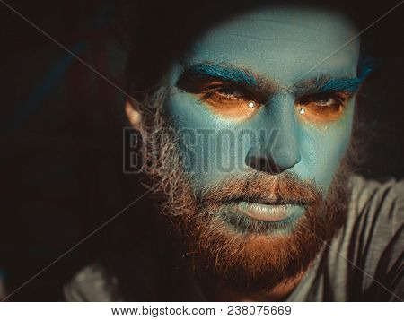 Portrait of a man with a blue make-up on his face. Stage make-up, like an alien, fantasy